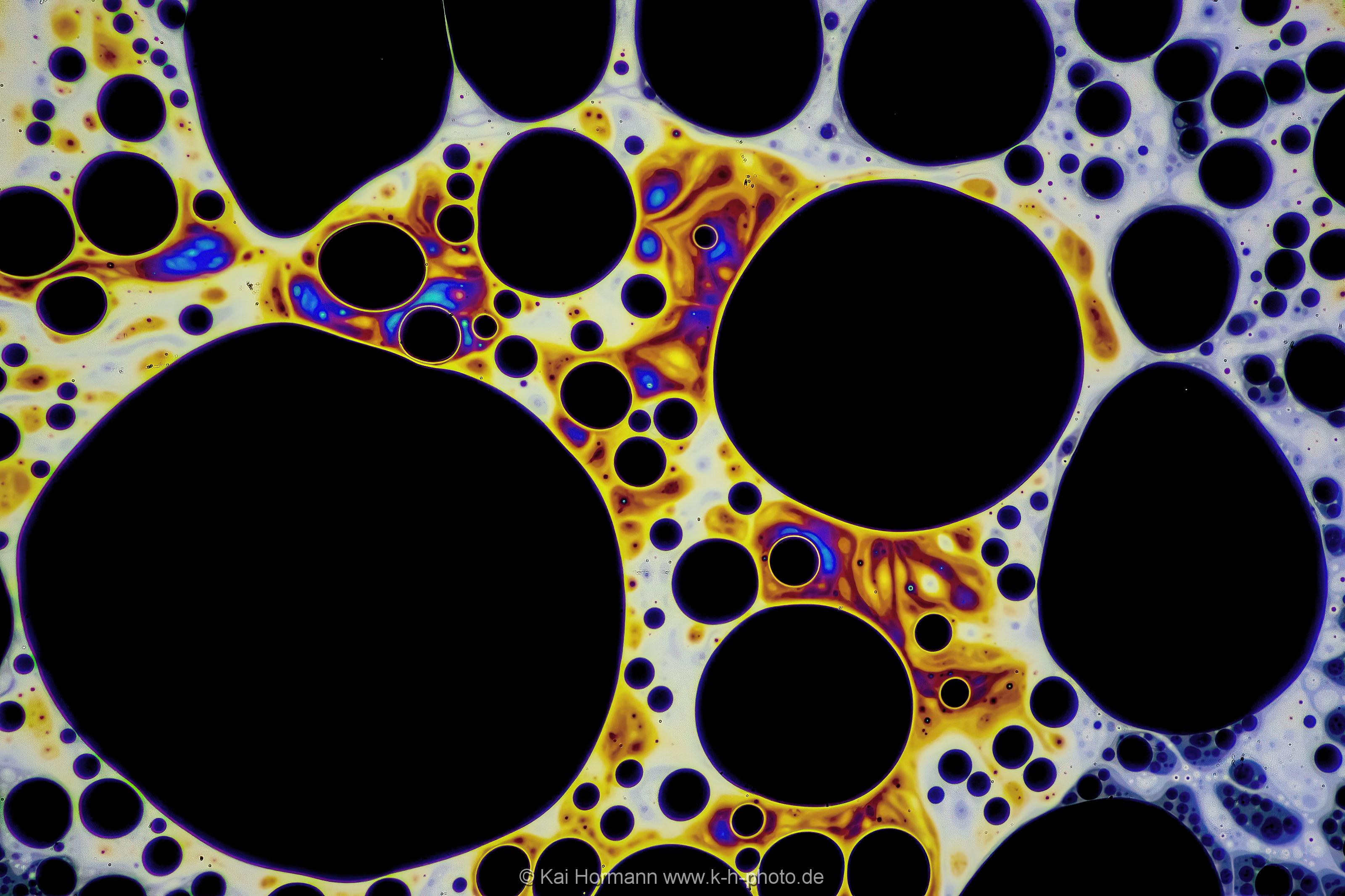 Strukturen und Farbmuster auf der Haut einer Seifenblase. Farb- und Interferenzmuster auf der Oberfläche einer Seifenblase. Vergrößerung ca. 50-100 X, Auflicht.