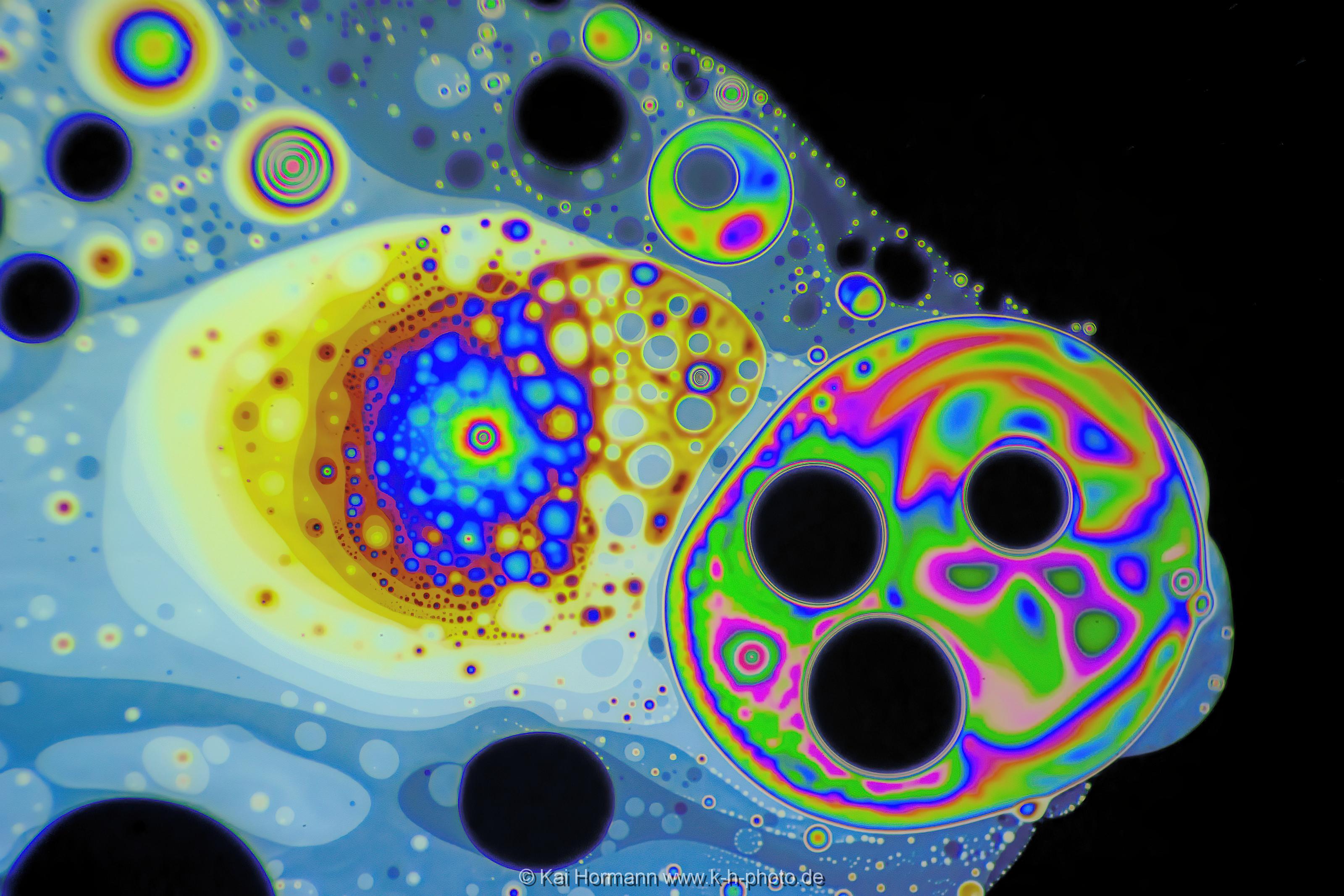 Strukturen und Farbmuster auf der Haut einer Seifenblase. Farb- und Interferenzmuster auf der Oberfläche einer Seifenblase. Vergrößerung ca. 50-100 X, Auflicht.